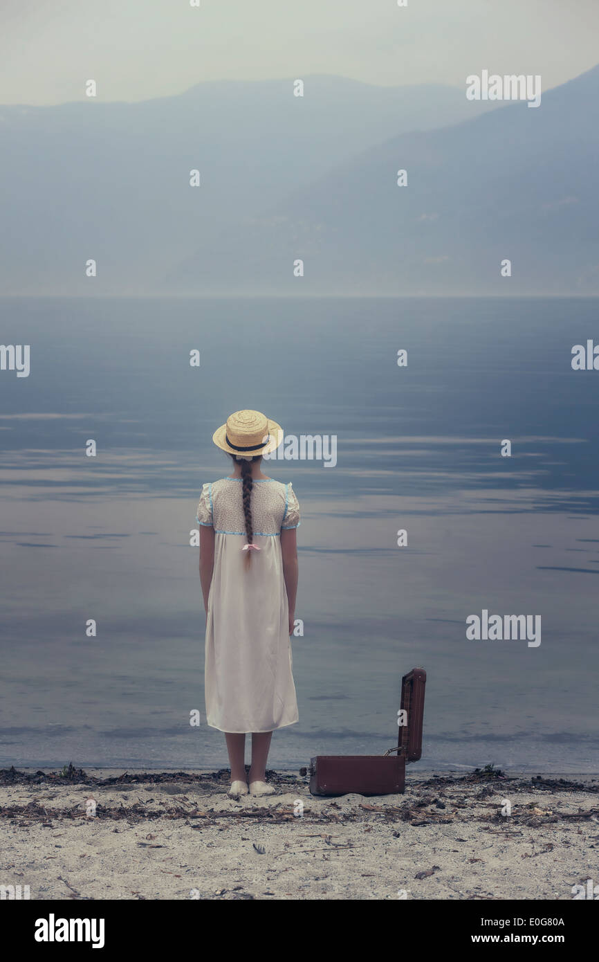 Une fille à un lac avec une valise ouverte Banque D'Images