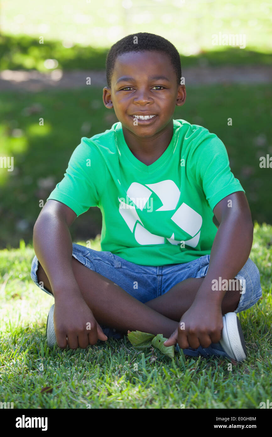 Jeune garçon assis sur l'herbe dans le recyclage tshirt Banque D'Images