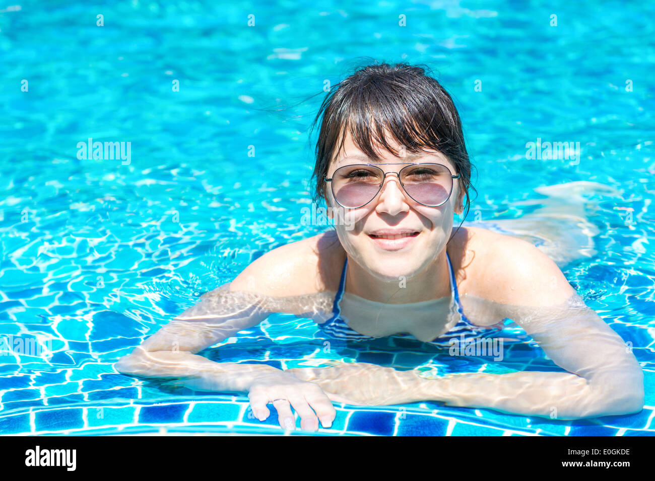 Portrait d'une belle jeune femme à lunettes flottant dans la piscine. Mode de vie sain photo Concept Banque D'Images