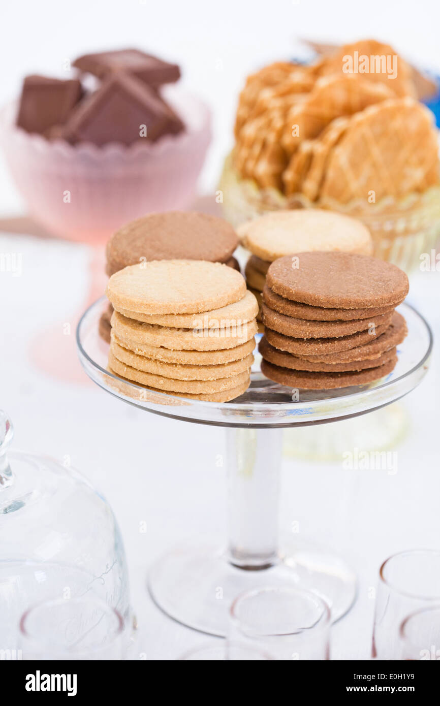 Libre de quatre piles de biscuit sec sur le verre au service de support avec morceaux de chocolat et les cookies dans des bols de gaufres en arrière-plan Banque D'Images