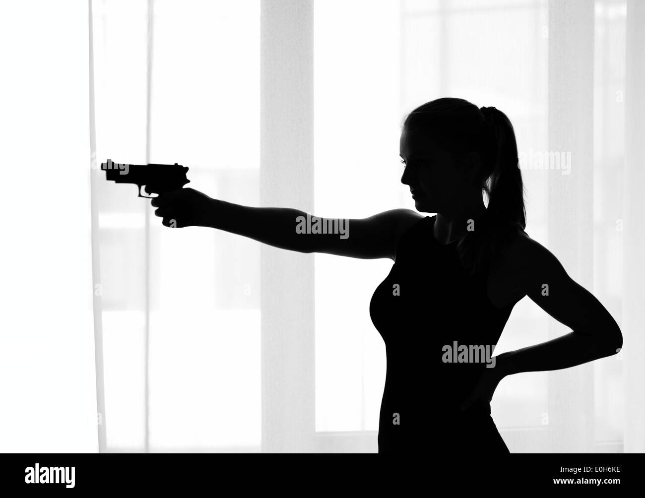 Silhouette de la jeune fille avec une arme à feu Banque D'Images