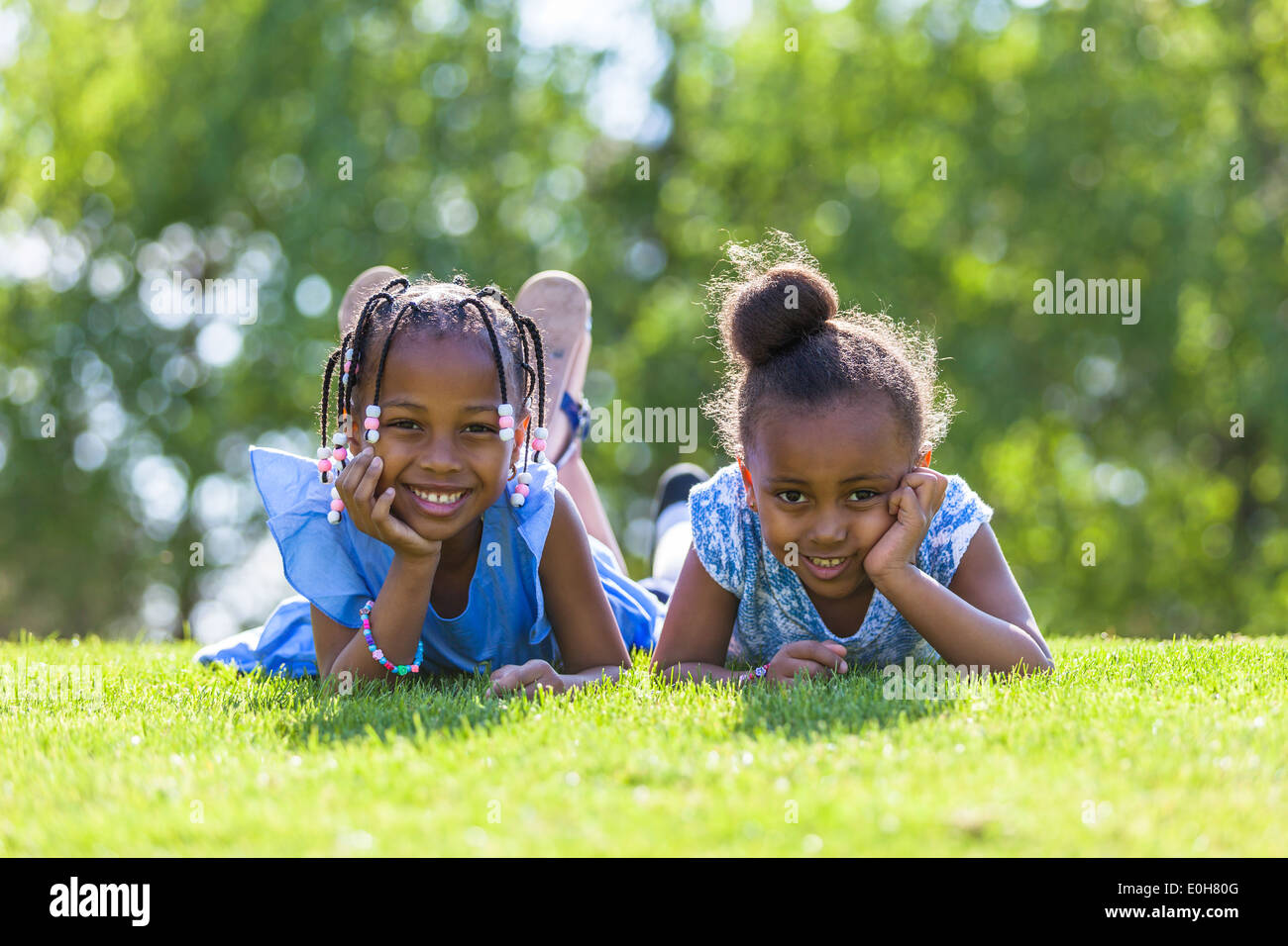 Outdoor portrait of a cute jeunes soeurs noir couché sur l'herbe et souriant - peuple africain Banque D'Images