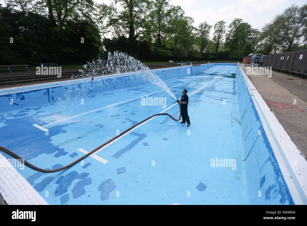 Un homme le remplissage d'une piscine extérieure avec un tuyau flexible Banque D'Images