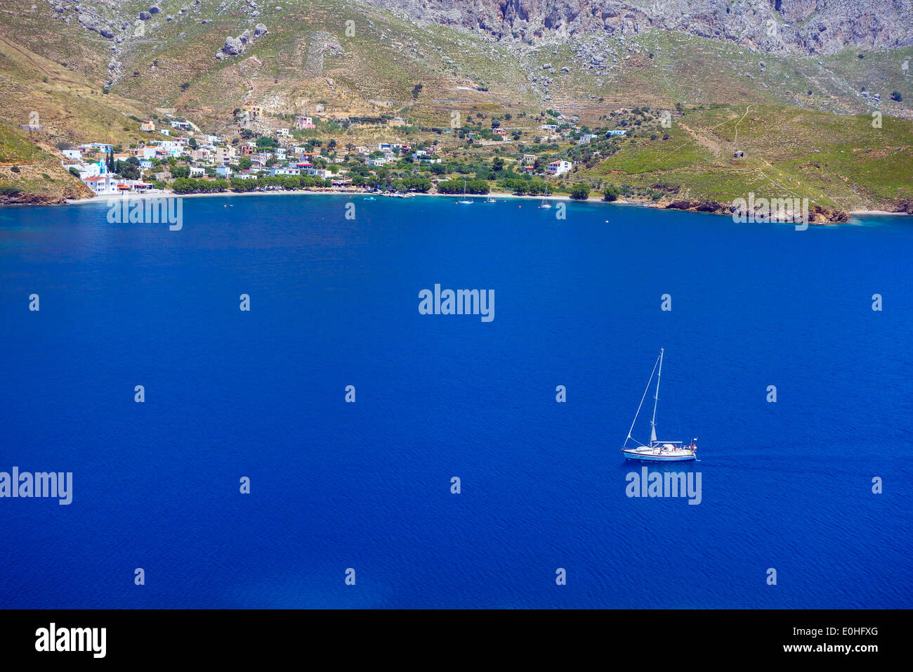 Yacht blanc sur la mer bleue de la baie, avec les collines environnantes, Grèce Banque D'Images