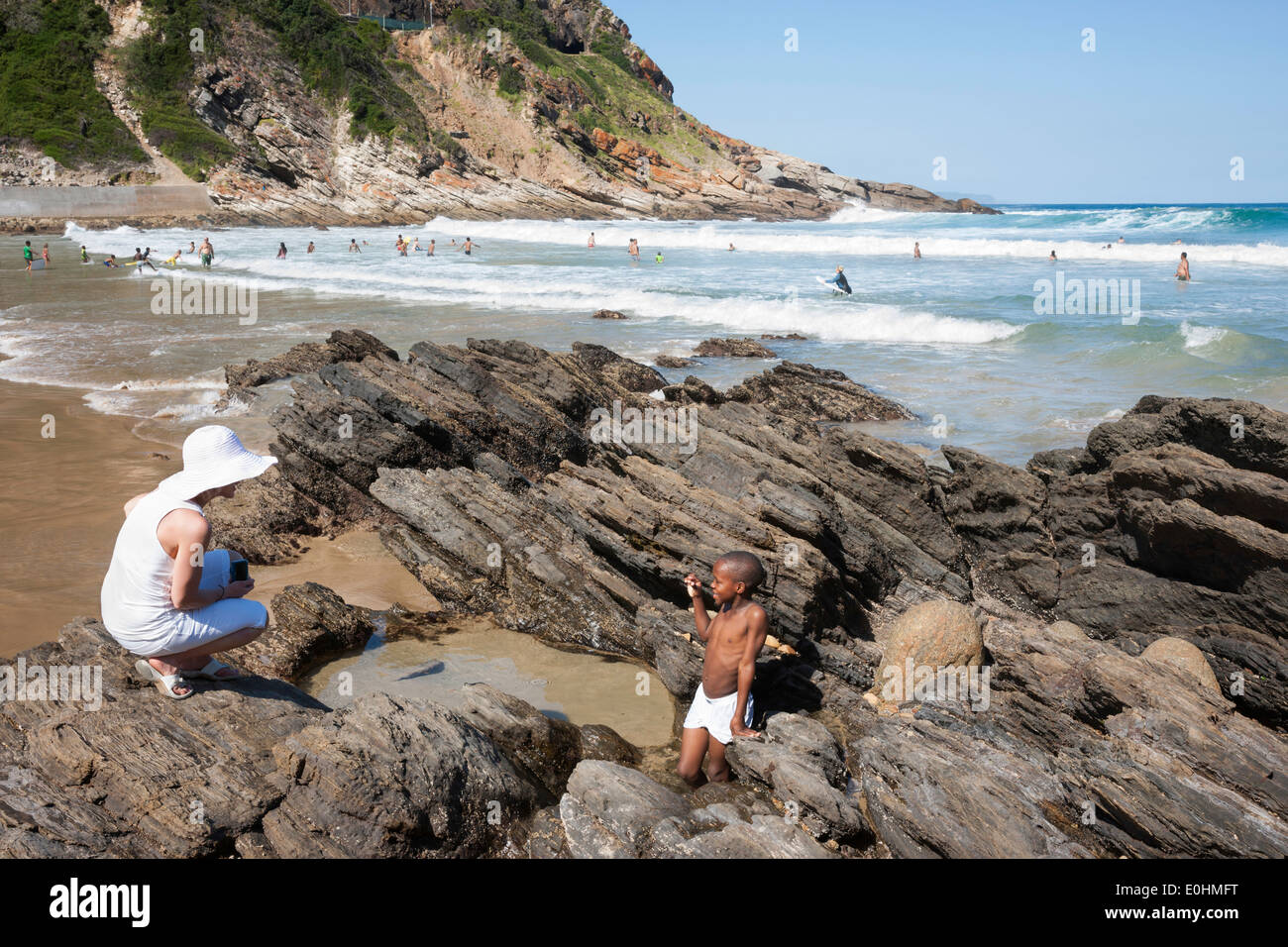 Portrait femme parlant avec un petit garçon africain attraper boule dans une piscine dans les rochers, plage de Victoria Bay, Western Cape, Garden Route Banque D'Images