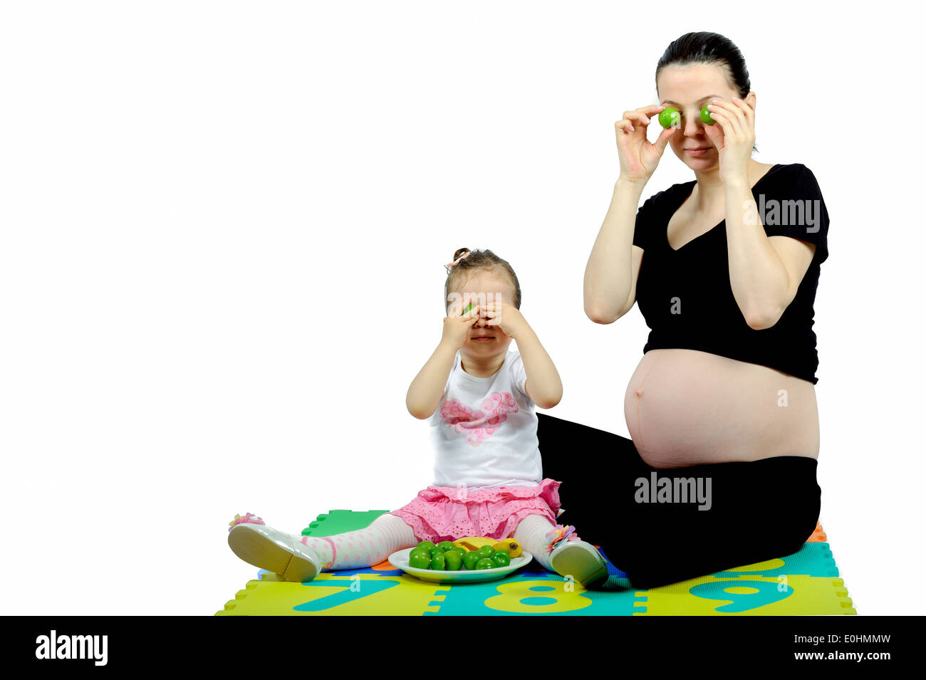 Premier enfant de jouer à sa mère enceinte avec fruits isolated on white Banque D'Images