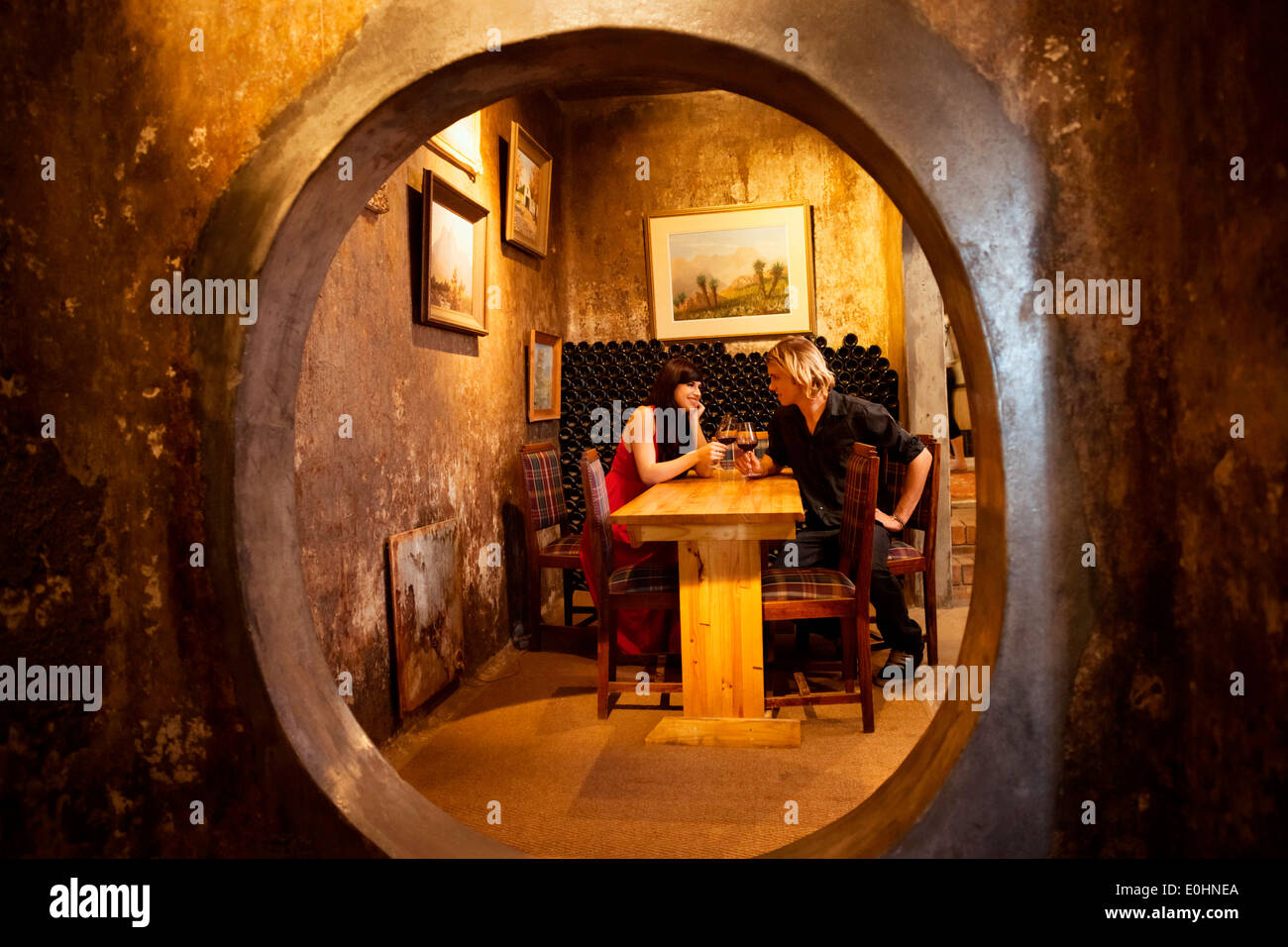 Couple romantique dans un tintement des verres de vin de niche privée tranquille à l'intérieur d'une winery, Afrique du Sud Banque D'Images