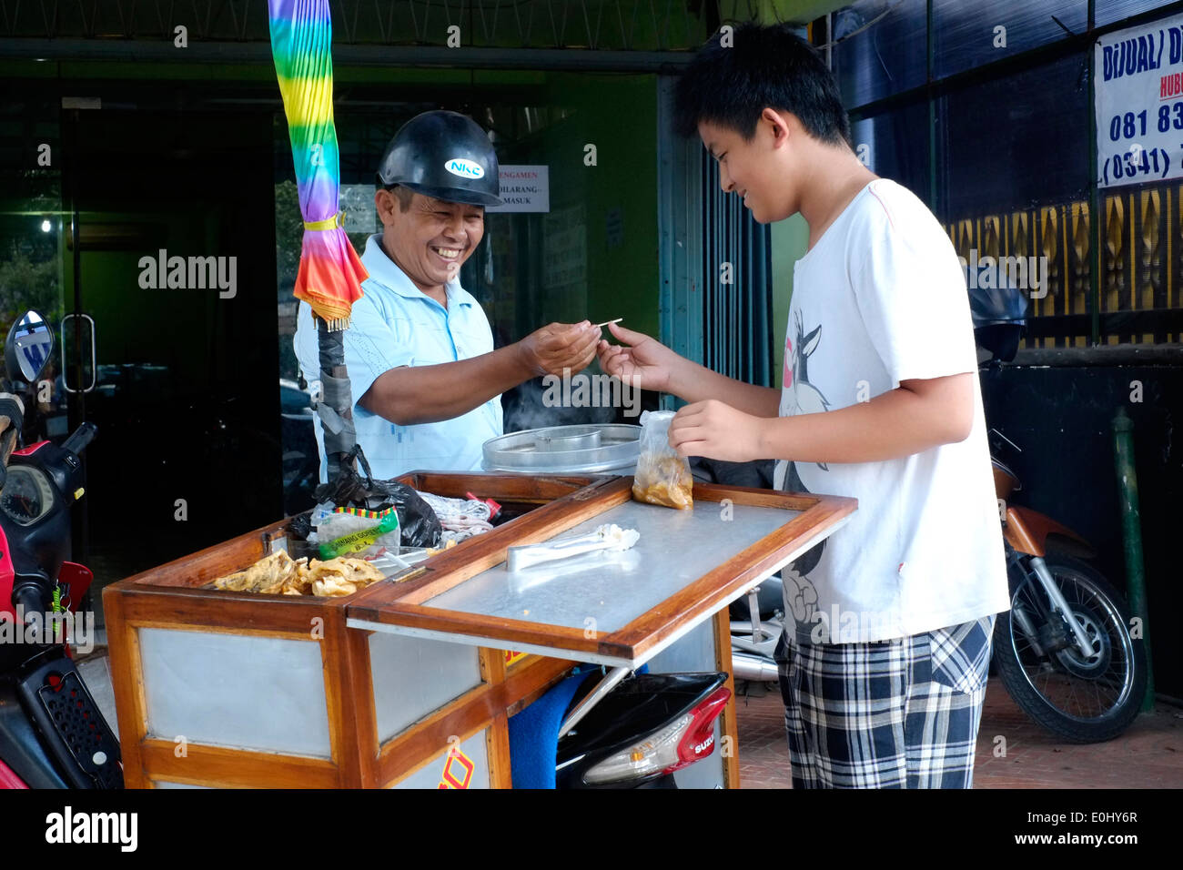 Jeune homme de la région l'achat de collations boulettes bakso vendeur de rue à malang indonésie Banque D'Images