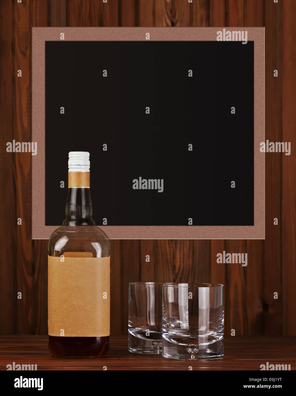 Deux verres avec de la glace pour le whiskey et bouteille sur fond de bois sombre. Banque D'Images