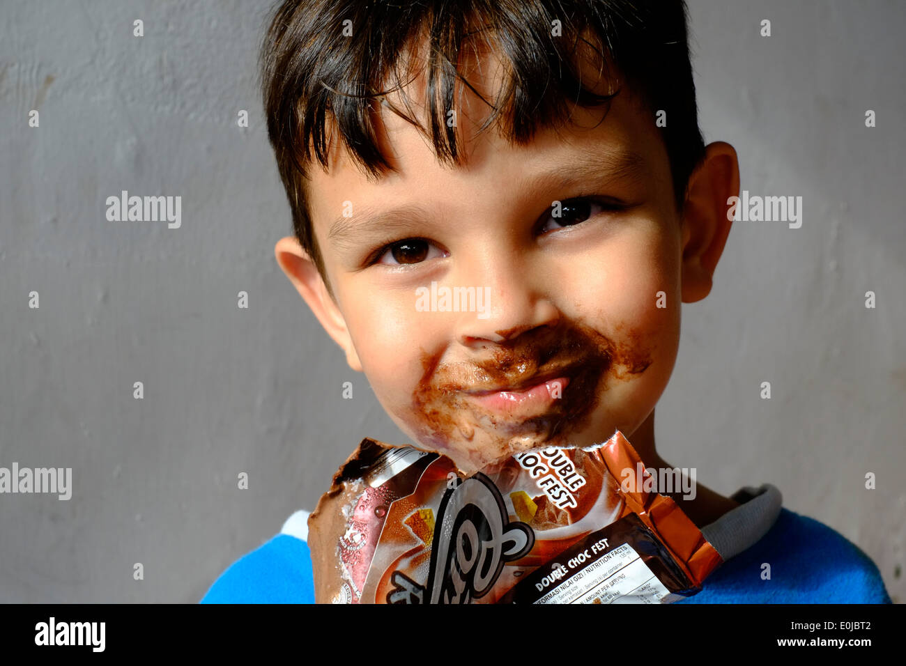 Jeune garçon mangeant une glace au chocolat et obtenir la plupart d'il enduit sur son visage Banque D'Images