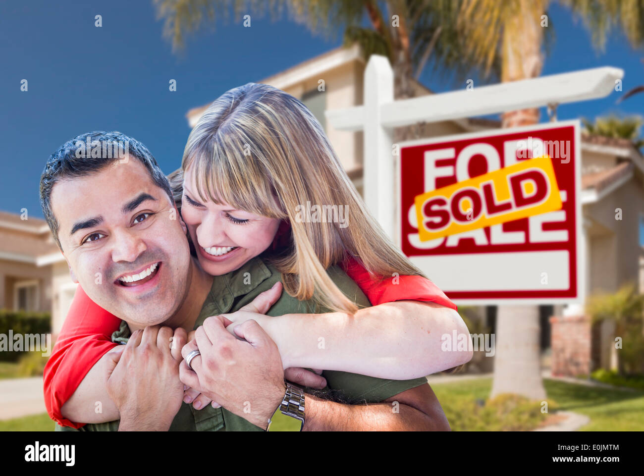 Heureux Hugging Young Couple in front of vendus Accueil Achat Immobilier signe et maison. Banque D'Images