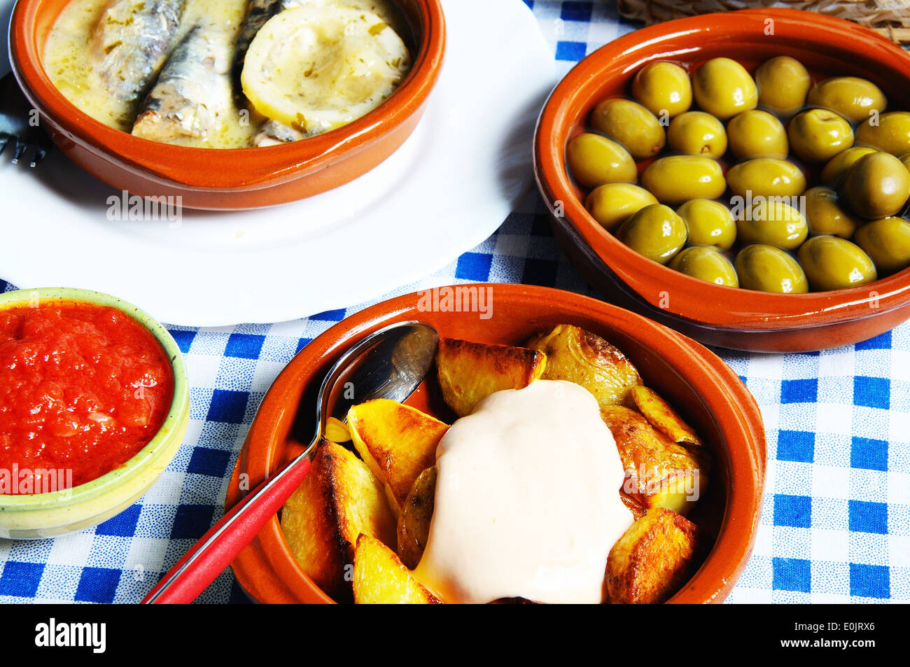 Des tapas espagnoles des patatas bravas, des olives vertes et les sardines en sauce au citron. Banque D'Images