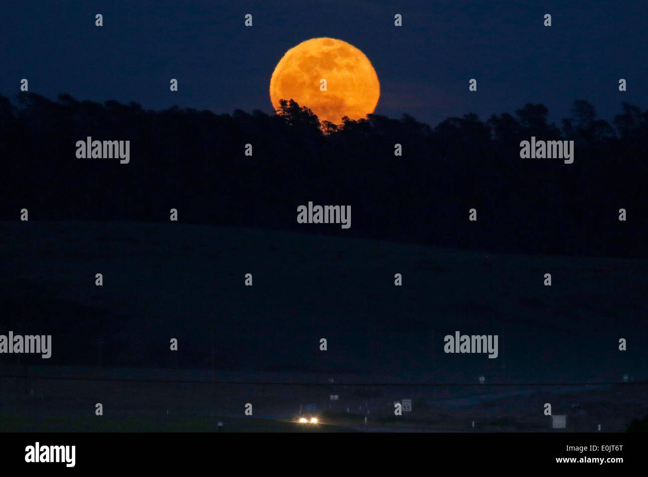 San Simeon, en Californie, USA. 14 mai, 2014. La pleine lune se lève sur un bosquet d'arbres comme la fumée dans l'atmosphère par les feux brûlant dans le centre et le sud de la Californie offrir la lune une lueur orange. Credit : Jonathan Alcorn/ZUMAPRESS.com/Alamy Live News Banque D'Images