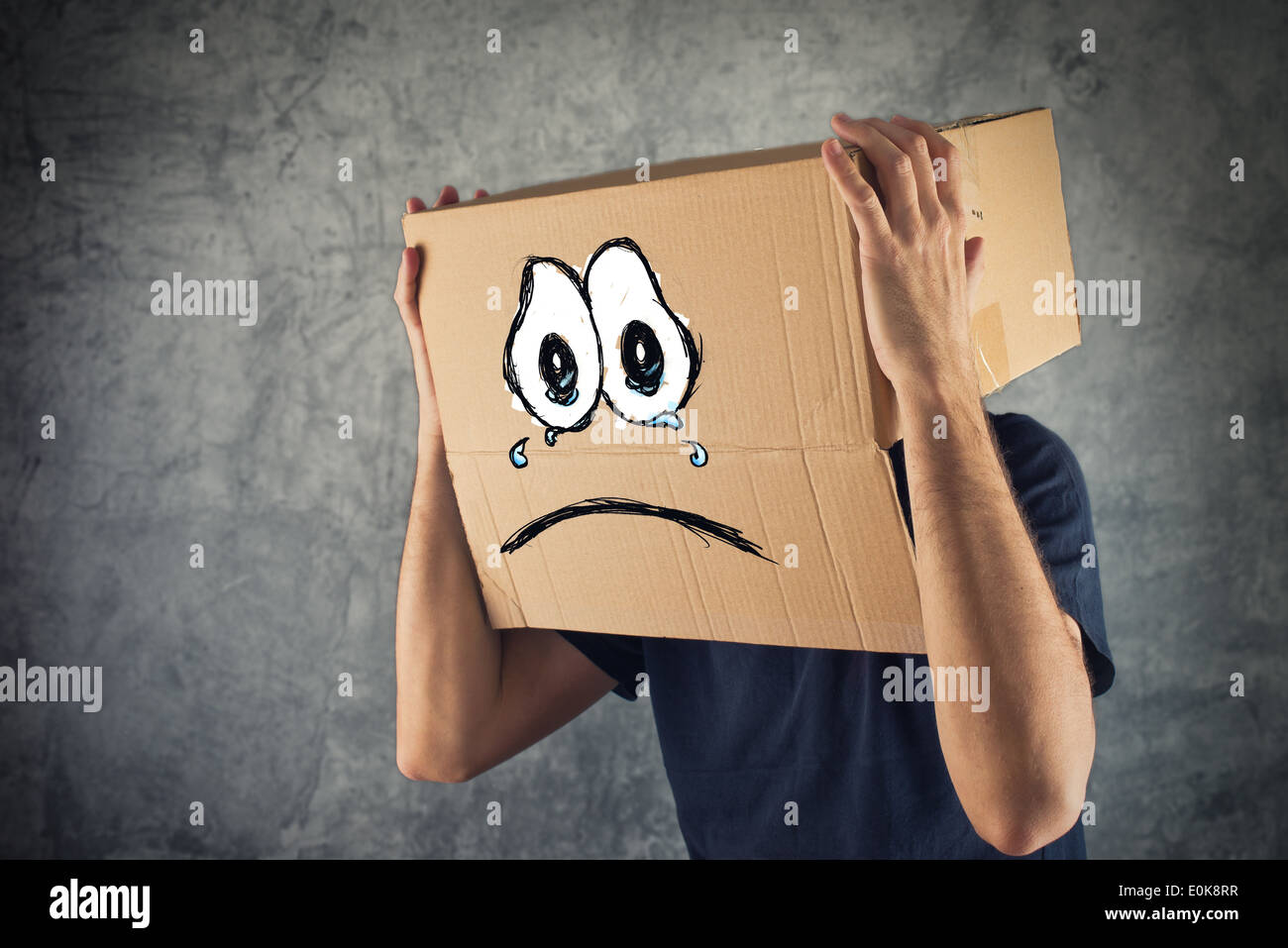 Homme avec boîte en carton sur la tête et visage pleurant triste expression. Concept de tristesse et dépression. Banque D'Images