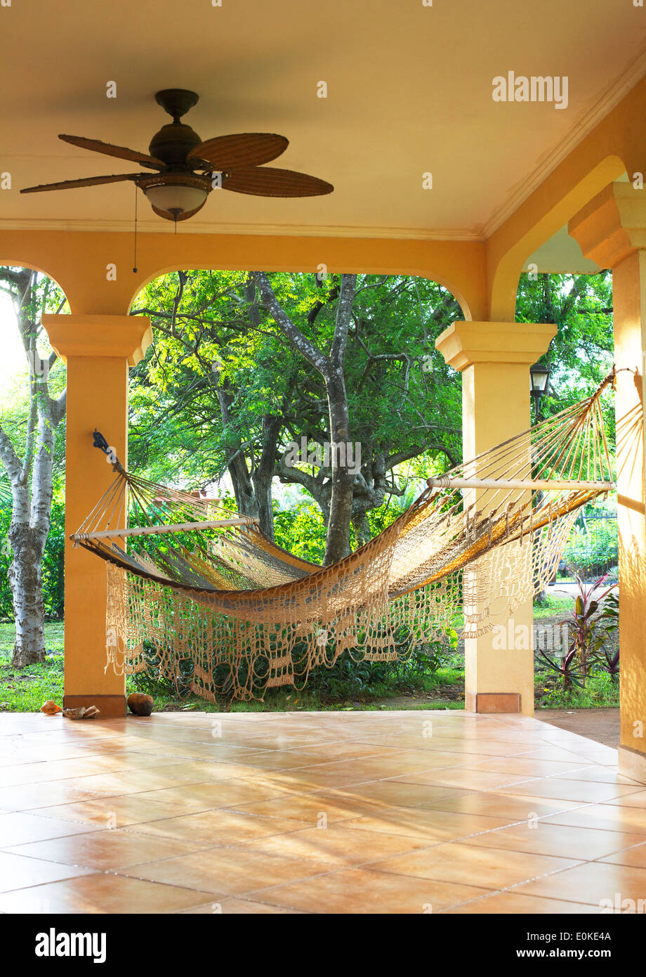 Un hamac est suspendu sur un porche ensoleillé avec les tropiques dans l'arrière-plan. Banque D'Images