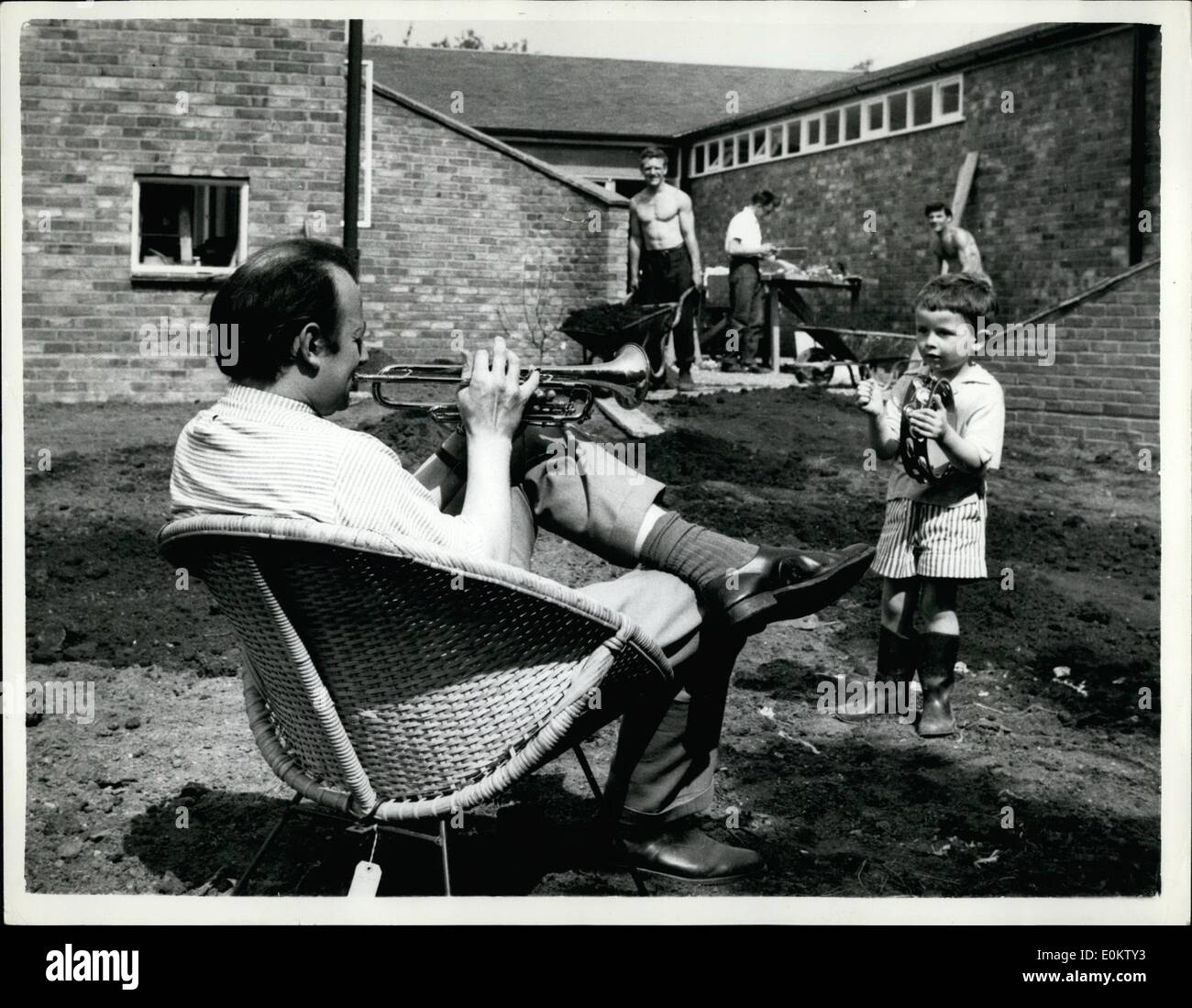 05 mai 1951 - ''la Chambre que construit humph'' - La maison qui est en construction à Barnet - pour Jazzman Humphrey Lyttelton - est presque terminée - en dépit des protestations de la part des membres du conseil local - qui prétendent que c'est comme un ''Cowahed'' il s'agit d'une COnstruction d'un étage en forme de 'U'..Humphrey et son épouse qimv. qu'il est moderne - sans être ultramoderne..Keystone Photo montre :- Comme adhérent obtient 'guidance' de son fils Stephen - comme il joue de la trompette hi dans le jardin de sa nouvelle maison - alors que les ouvriers continuent à l'arrière-plan. Banque D'Images