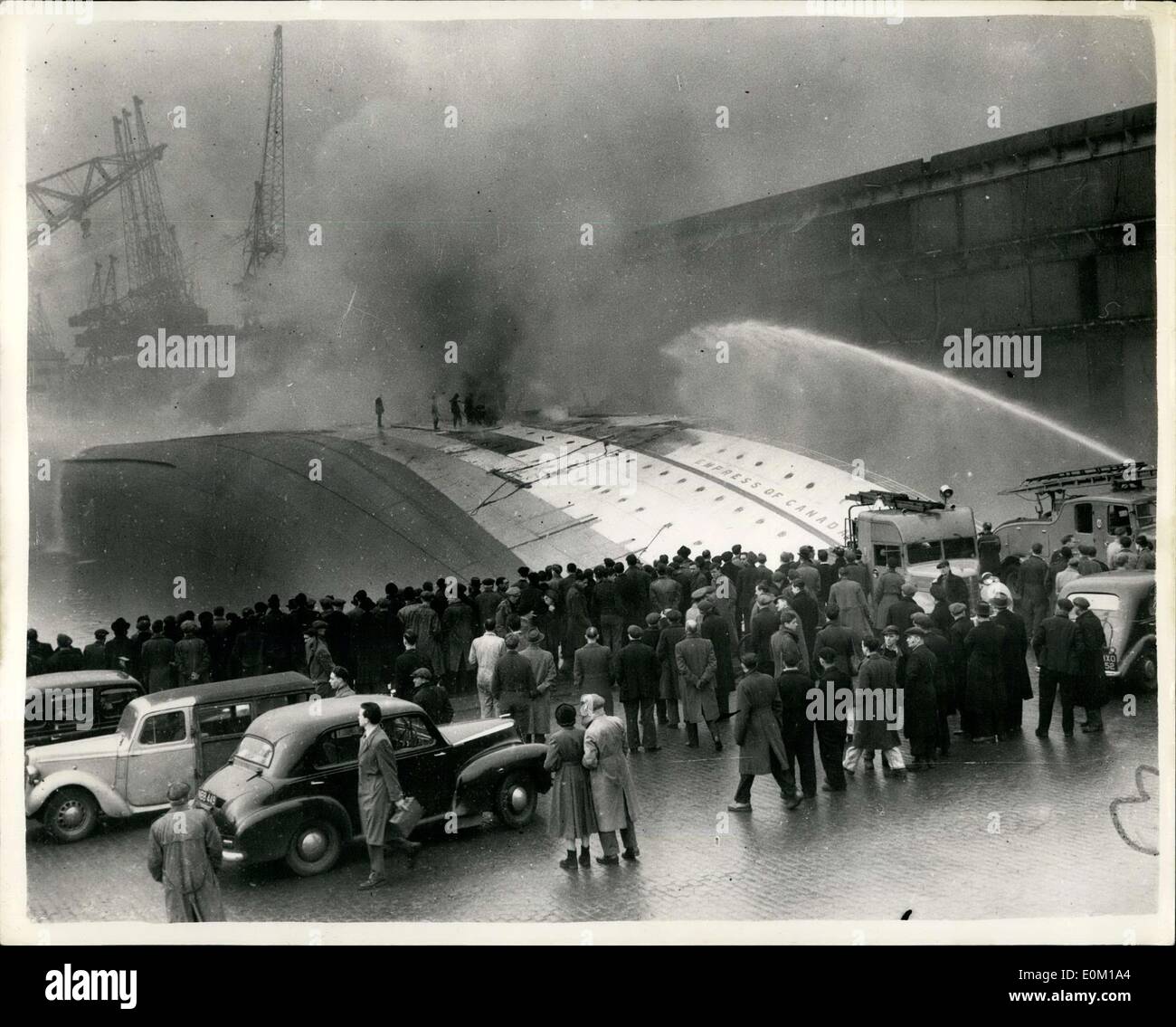 26 janvier 1953 - a chaviré Empress of Canada brûle encore : Photo montre : la foule sur le quai regarder pompiers joue toujours leurs flexibles sur l'Empress of Canada chaviré à Gladstone Dock, Liverpool. Banque D'Images