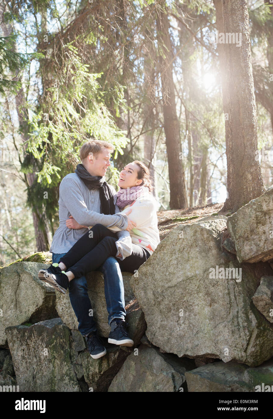 Jeune couple dans la nature repose sur de gros rochers dans les bois lors d'un trek. Assis sur le bord qu'elles détiennent sur l'une à l'autre. Banque D'Images