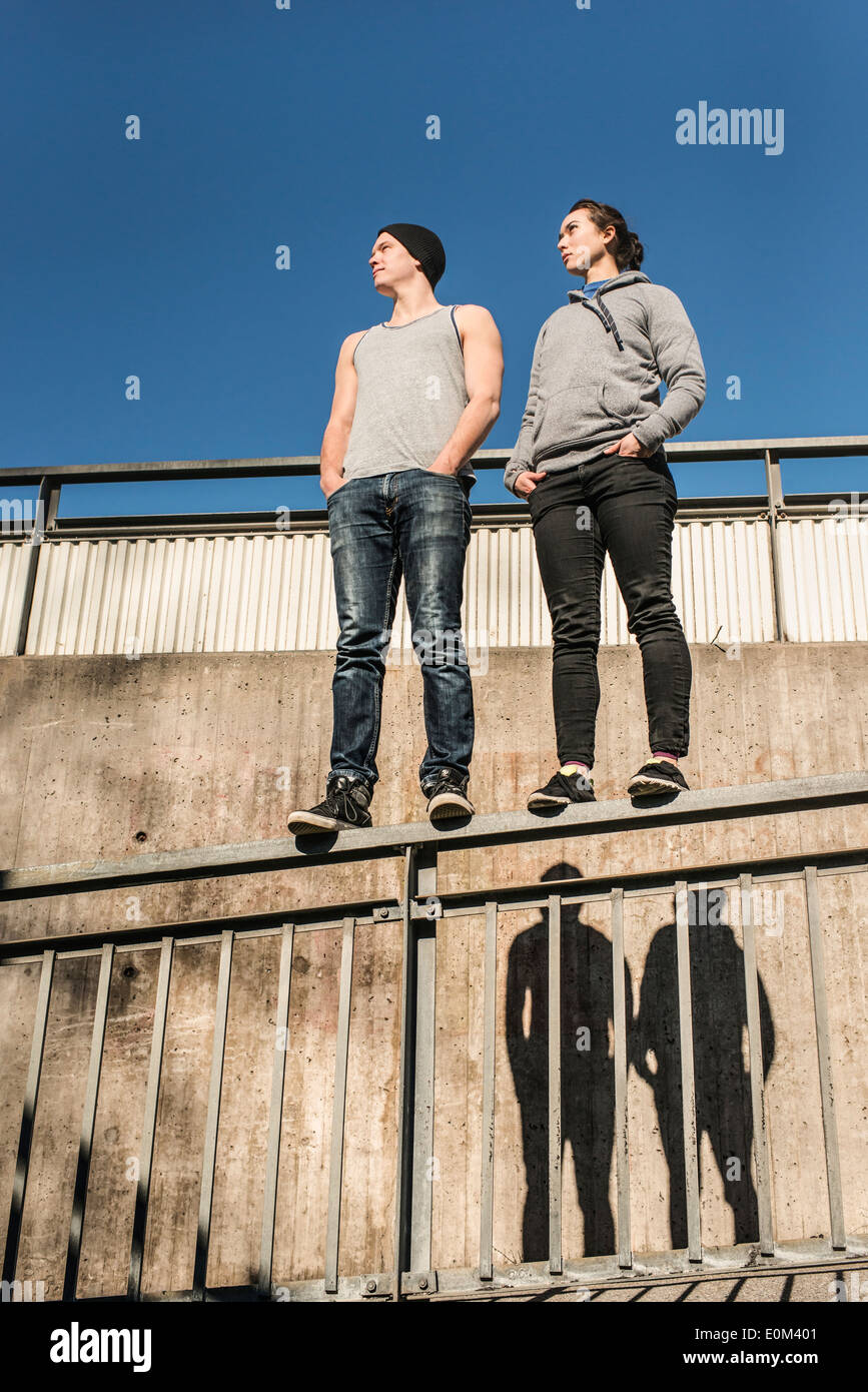 Portrait de jeune homme informelle et détendue et la femme en équilibre sur rail en zone urbaine. Banque D'Images