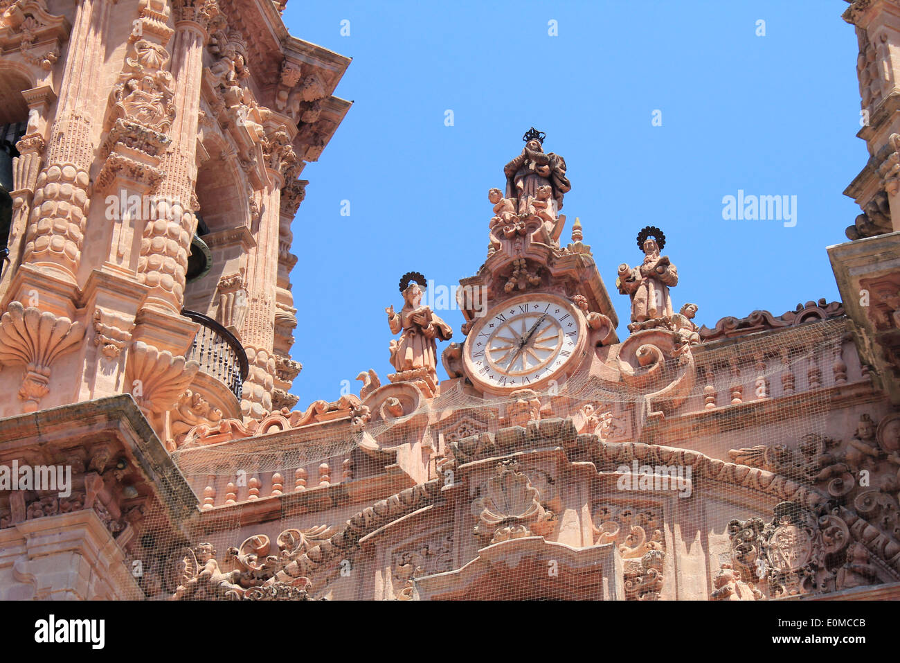 Un gros plan de l'horloge et les figures sculptées en pierre rose sur la façade de l'église de Santa Prisca à Taxco, Mexique Banque D'Images