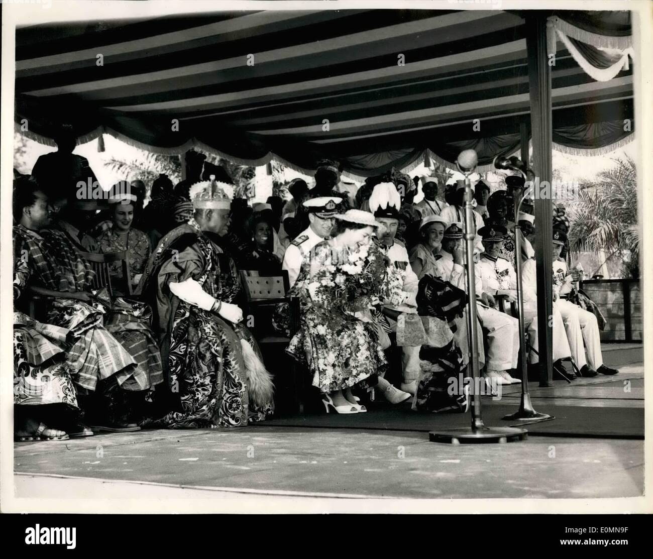 01 janv., 1956 - REINE ARRIVE AU NIGERIA...FOLOSHADE PRÉSENTE UN BOUQUET... PHOTO : KEYSTONE MONTRE- H.M. TRE REINE se penche en avant pour bouquet reçoit à partir de trois ans, fille d'FOLOSHADE LAMSON le président du Conseil - au cours de la cérémonie officielle de bienvenue à la Reine à son arrivée à LA008, le Nigeria. La petite fille - habillés en costume tribal Yoruba - un énorme turban qui presque englouti son était tellement qu'elle nervouenees avec presque déboulonnée - mais Manageded la Reine de "sauver" le bouquet. Sur la gauche est le chef d'OBA ADTNIJI Lagos.ADELLE II - qui étaient d'une couronne - et megnifioient Banque D'Images