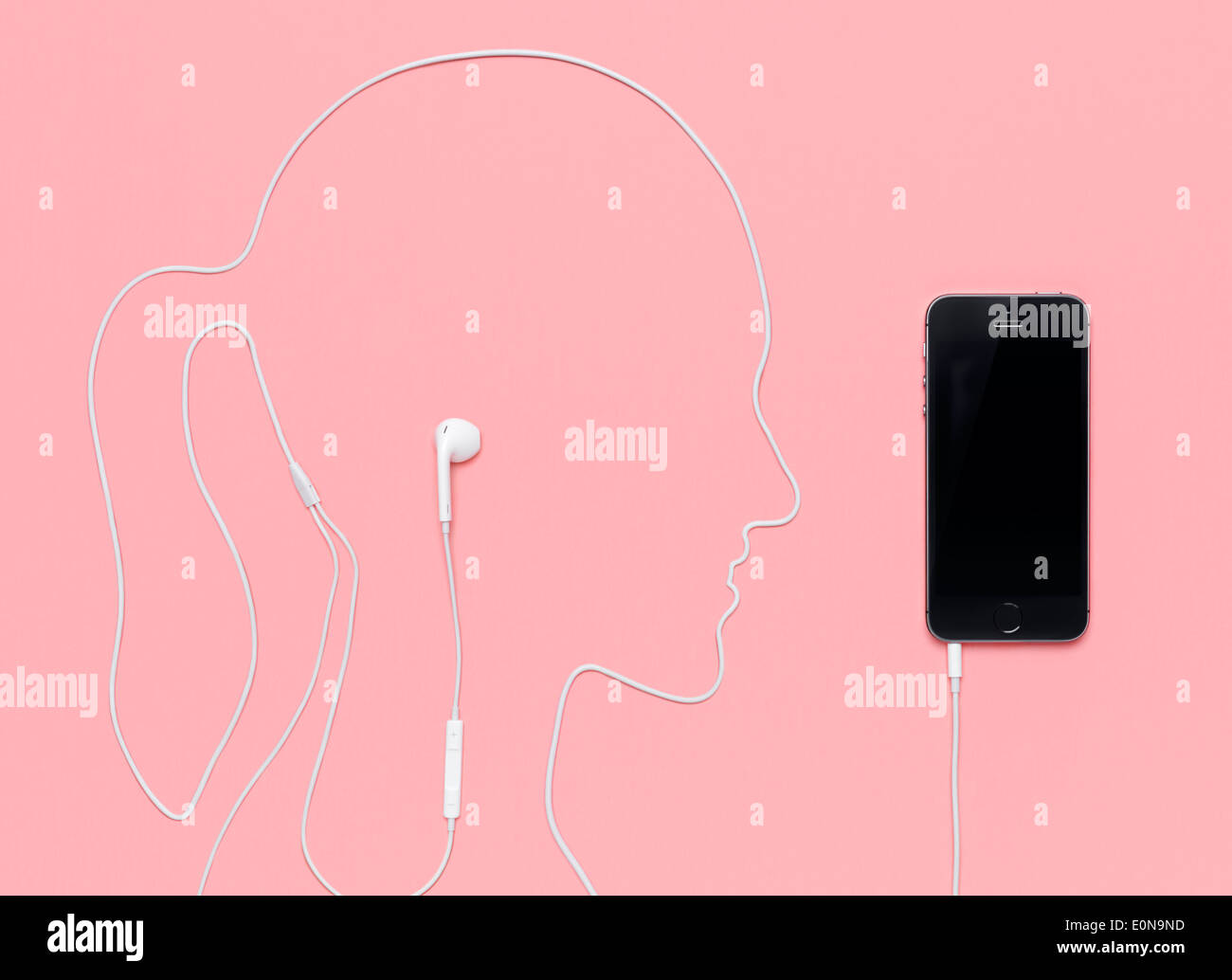 Femme chef contours pris par un cordon des écouteurs branchés sur l'iPhone 5s smartphone. Concept de la musique sur fond rose. Banque D'Images