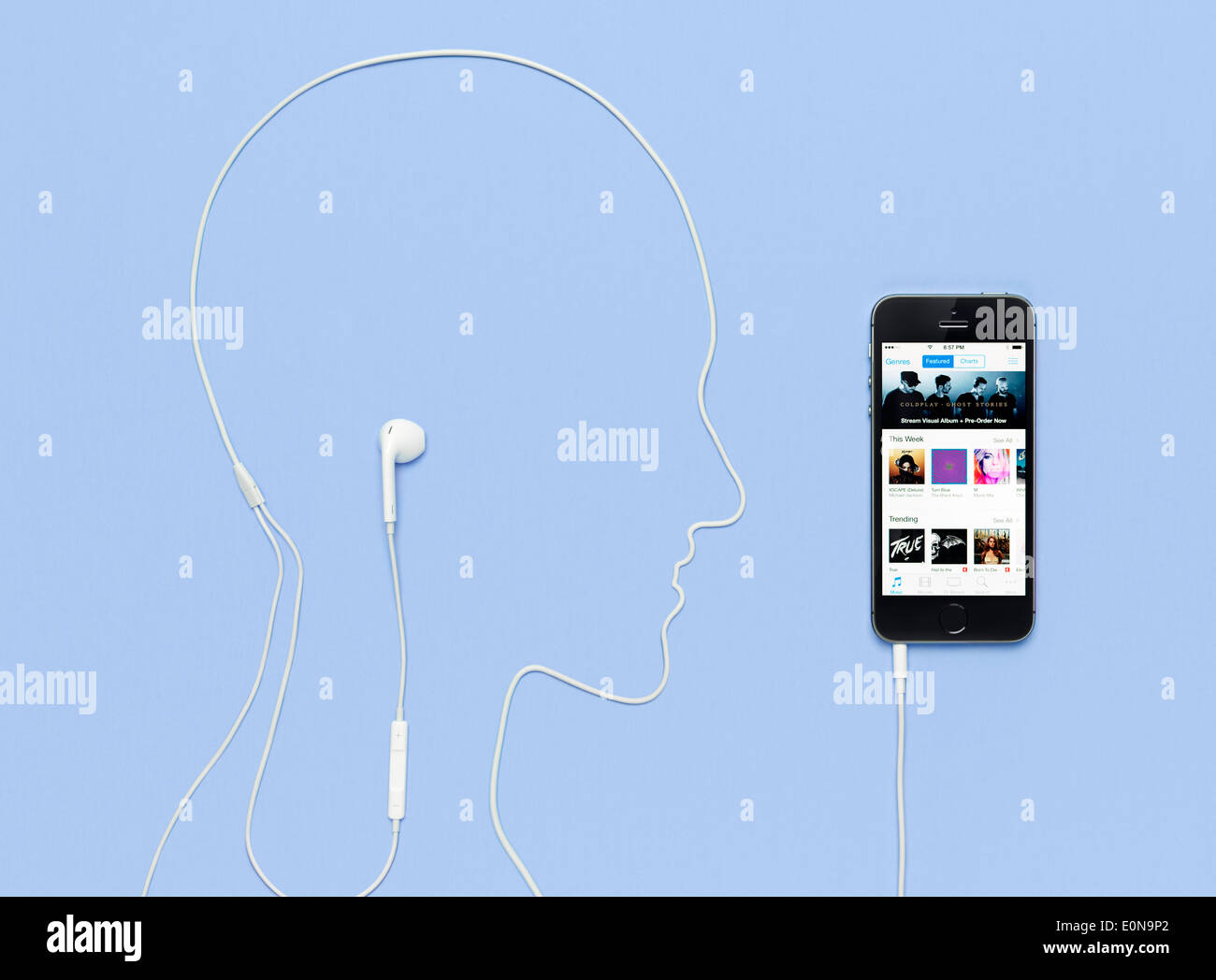 Tête d'homme contours pris par un cordon casque branché sur l'iPhone 5s téléphone avec iTunes music store sur son afficheur. Concept créatif Banque D'Images