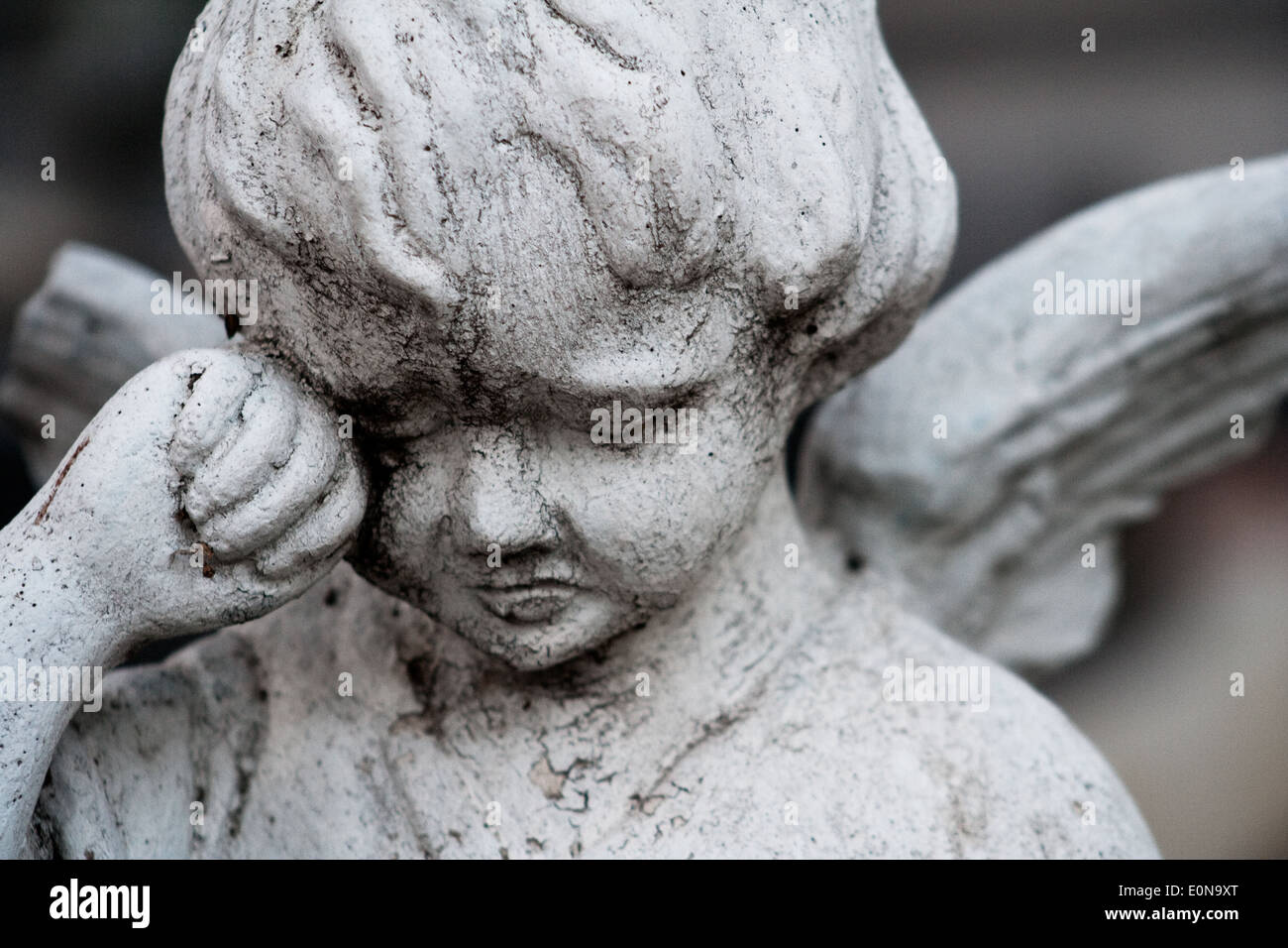 Une statue d'un ange enfant avec une aile cassée pleure Banque D'Images