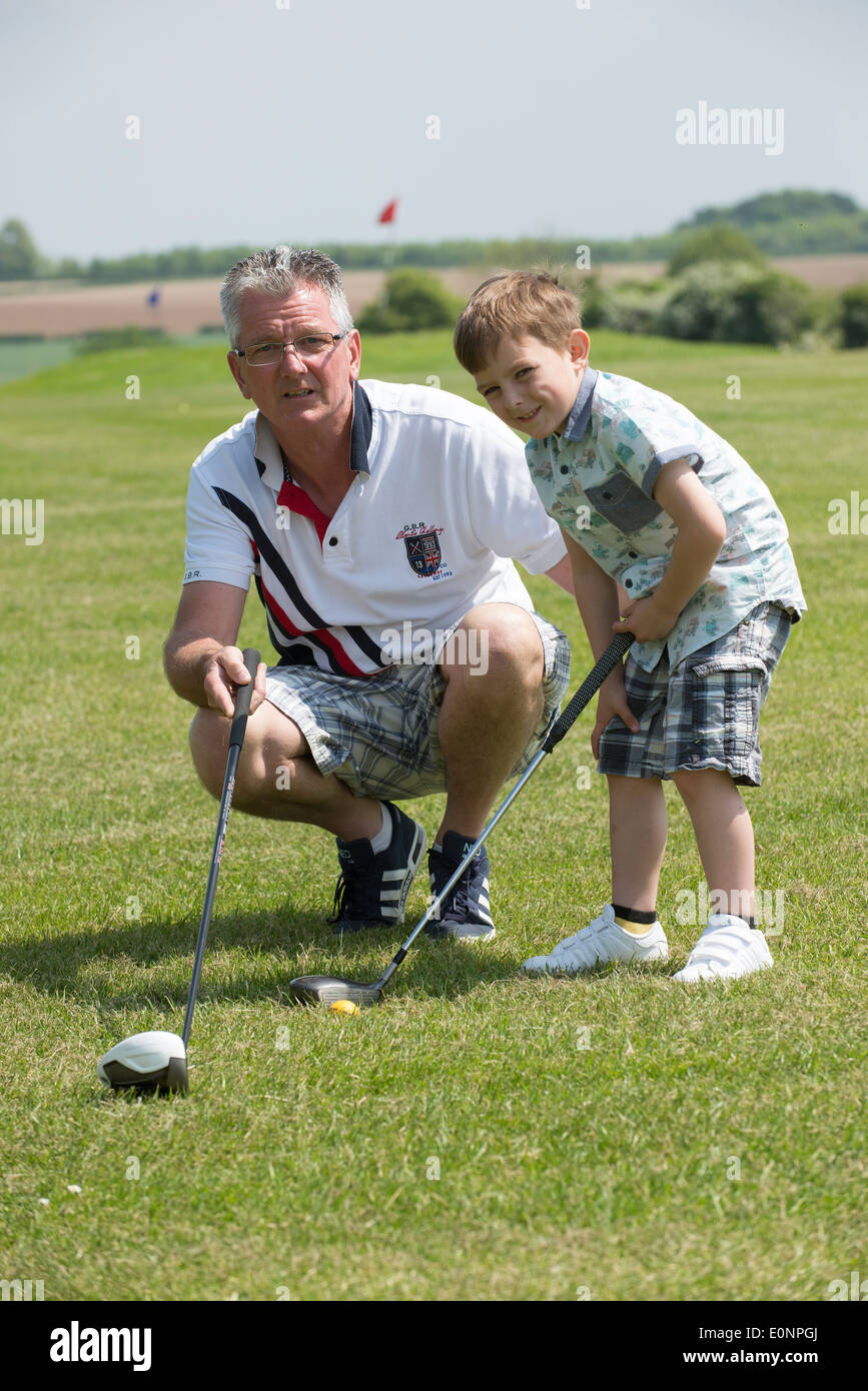Portrait de golfeurs juniors et seniors clubs tenant leur grand-père d'enseigner son jeune petit-fils de jouer le golf Hampshire Angleterre Banque D'Images