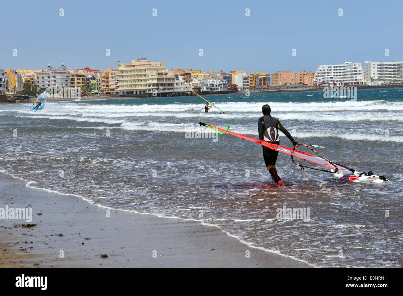 Wind surfer sur la plage d'El Medano, Tenerife avec voile et conseil, ville de El Medano en arrière-plan Banque D'Images