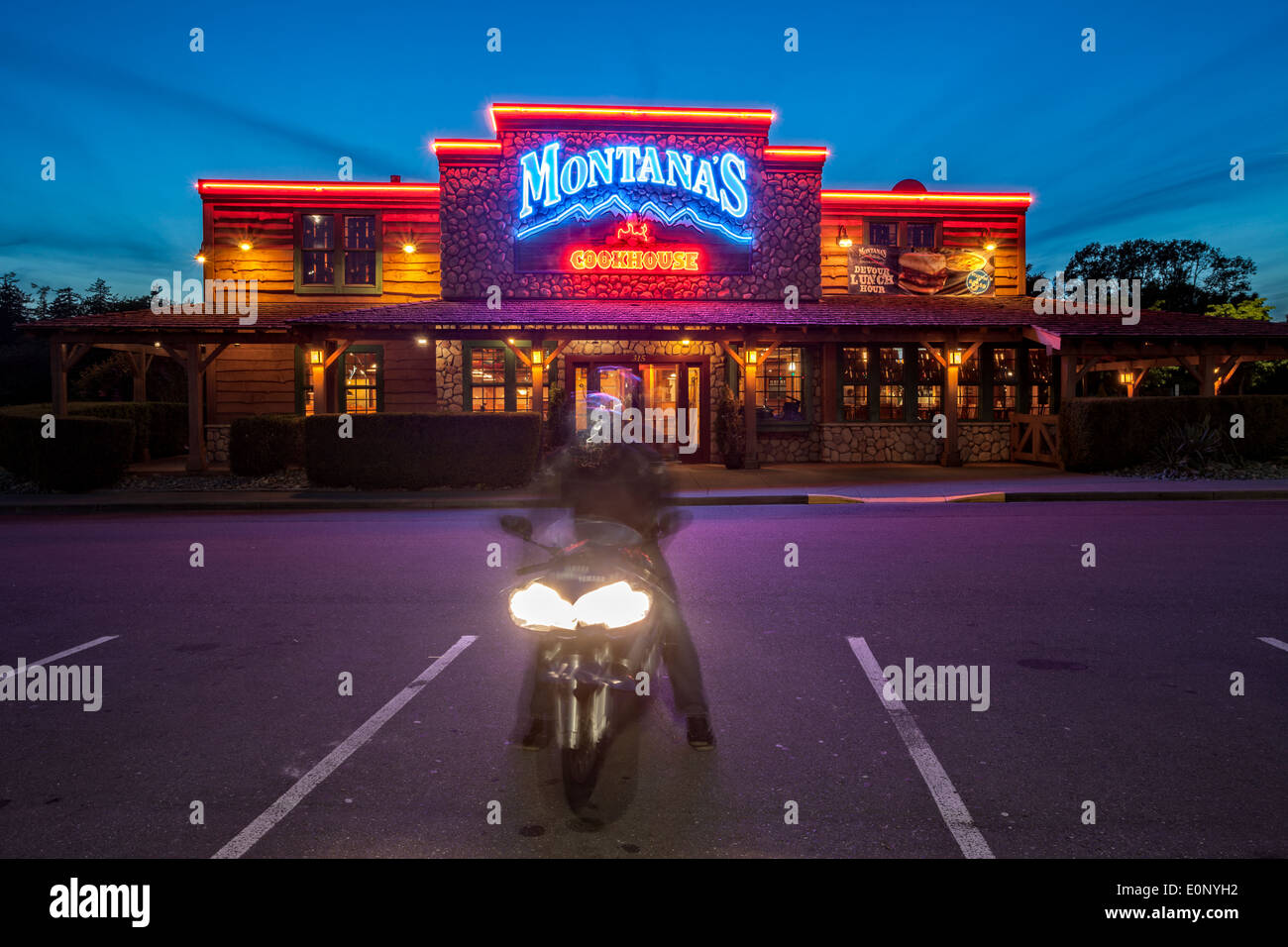 Pilote moto en dehors de Montana's Cookhouse restaurant au crépuscule-Victoria, Colombie-Britannique, Canada. Banque D'Images