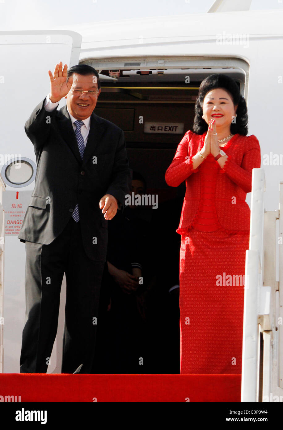 Phnom Penh. 18 mai, 2014. Le Premier ministre cambodgien Hun Sen (L) et son épouse Bun Rany geste à l'aéroport international de Phnom Penh à Phnom Penh le 18 mai 2014. Hun Sen s'est rendu à Shanghai dans l'est de la Chine dimanche matin pour participer au 4ème sommet de la Conférence sur l'interaction et des mesures de confiance en Asie (CICA), qui aura lieu le mardi et le mercredi. © Sovannara/Xinhua/Alamy Live News Banque D'Images