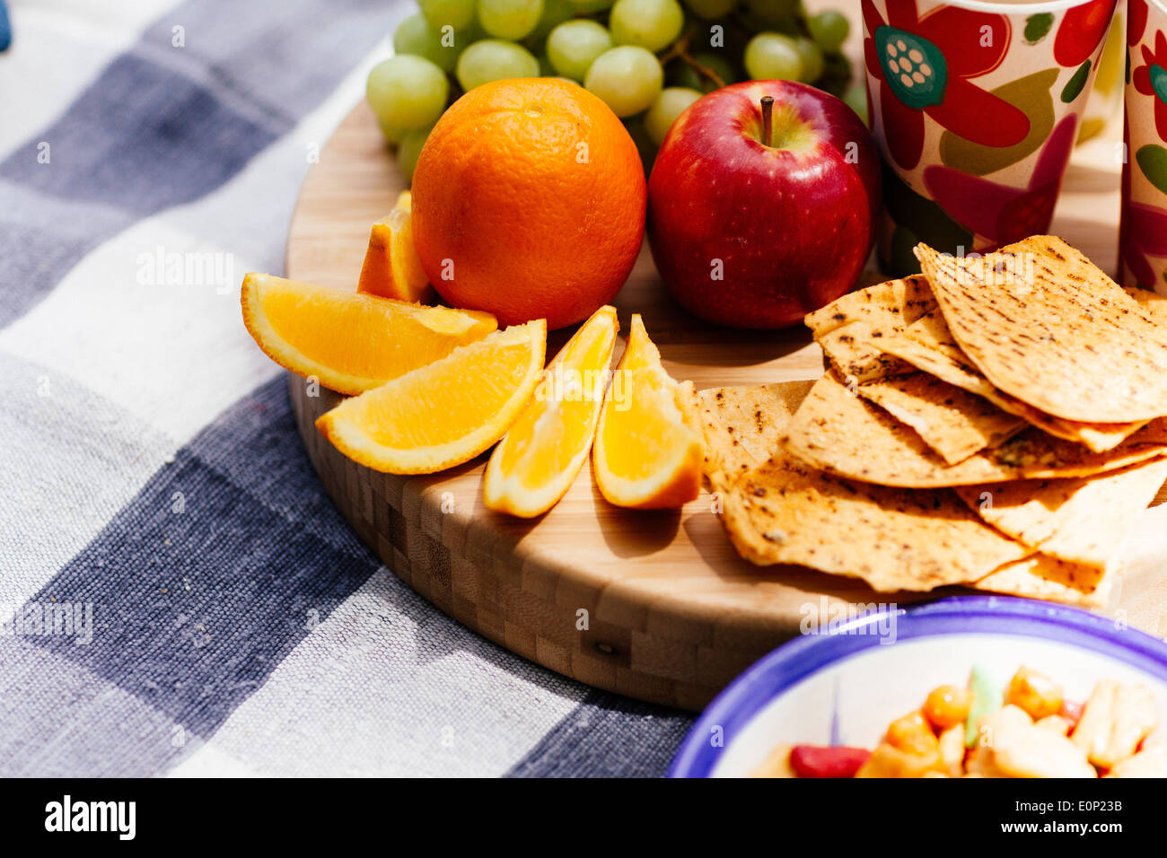 Des fruits frais et des collations assis sur planche de bois on picnic blanket Banque D'Images