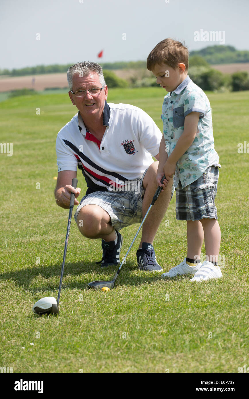 Portrait de golfeurs juniors et seniors clubs tenant leur grand-père d'enseigner son jeune petit-fils de jouer le golf Hampshire Angleterre Banque D'Images