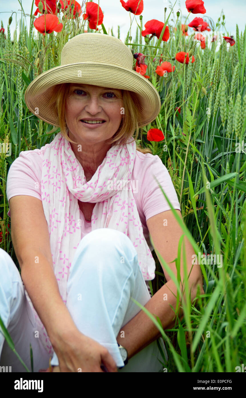 Woman with hat sitting on meadow Banque D'Images