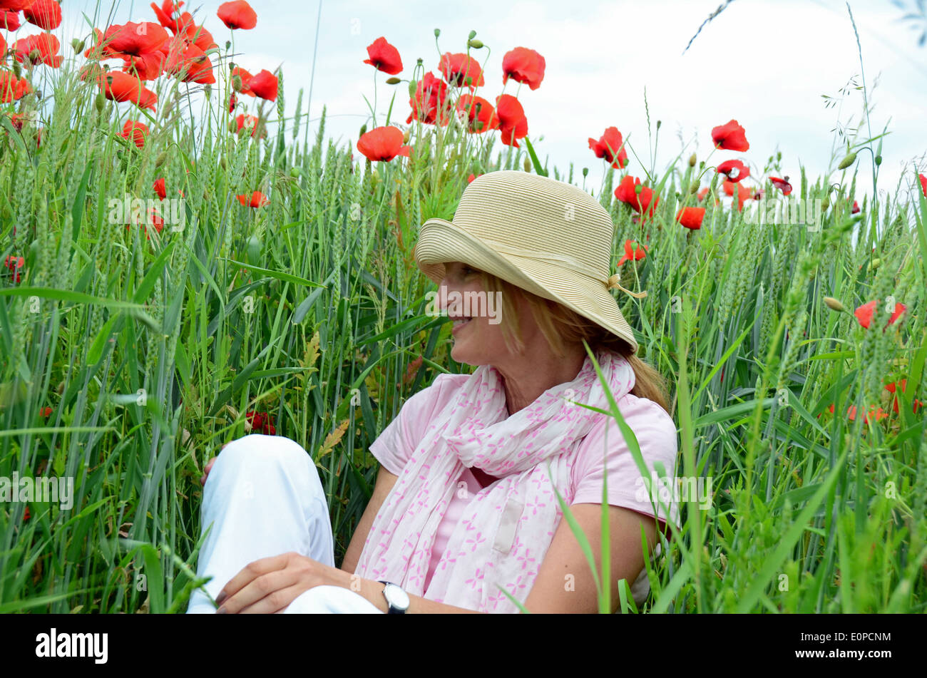 Woman with hat sitting on meadow Banque D'Images