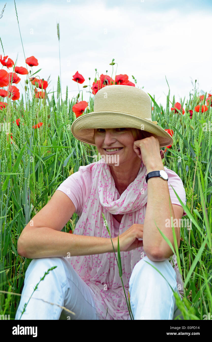 Woman with hat sitting on meadow Banque D'Images