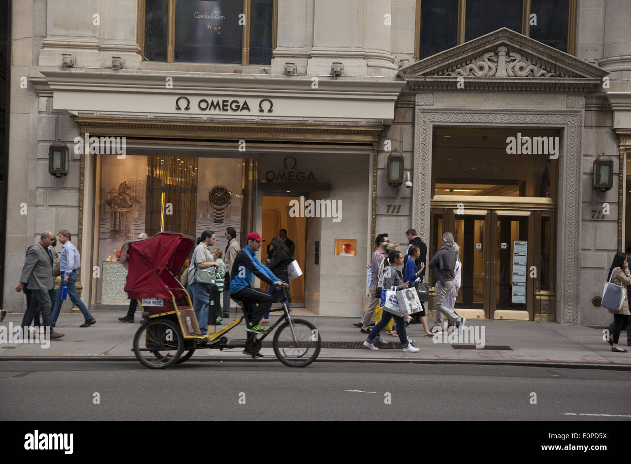 Pedicab & piétons sur la 5e Avenue à Manhattan, en passant l'Omega watches store. Banque D'Images