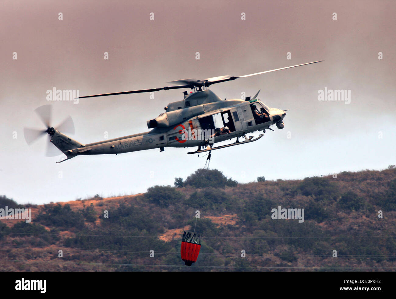 Un hélicoptère de l'US Marine Corps transporte l'eau à l'aide d'un godet de Bambi pour aider à combattre le tomahawk et Las Pulgas friches comme ils brûlent les contreforts 16 Mai 2014 autour de Camp Pendleton, en Californie. Plus de 13 000 évacuations forcées des personnes à leur domicile comme le feu a brûlé dans le comté de San Diego. Banque D'Images