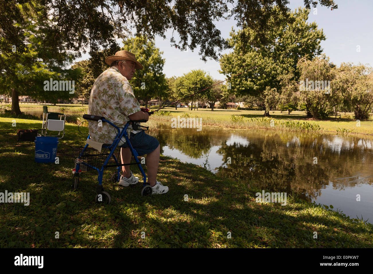 Vieil homme de l'emplacement à bord de l'eau dans la région de Leesburg, en Floride, la pêche dans son walker président. Banque D'Images