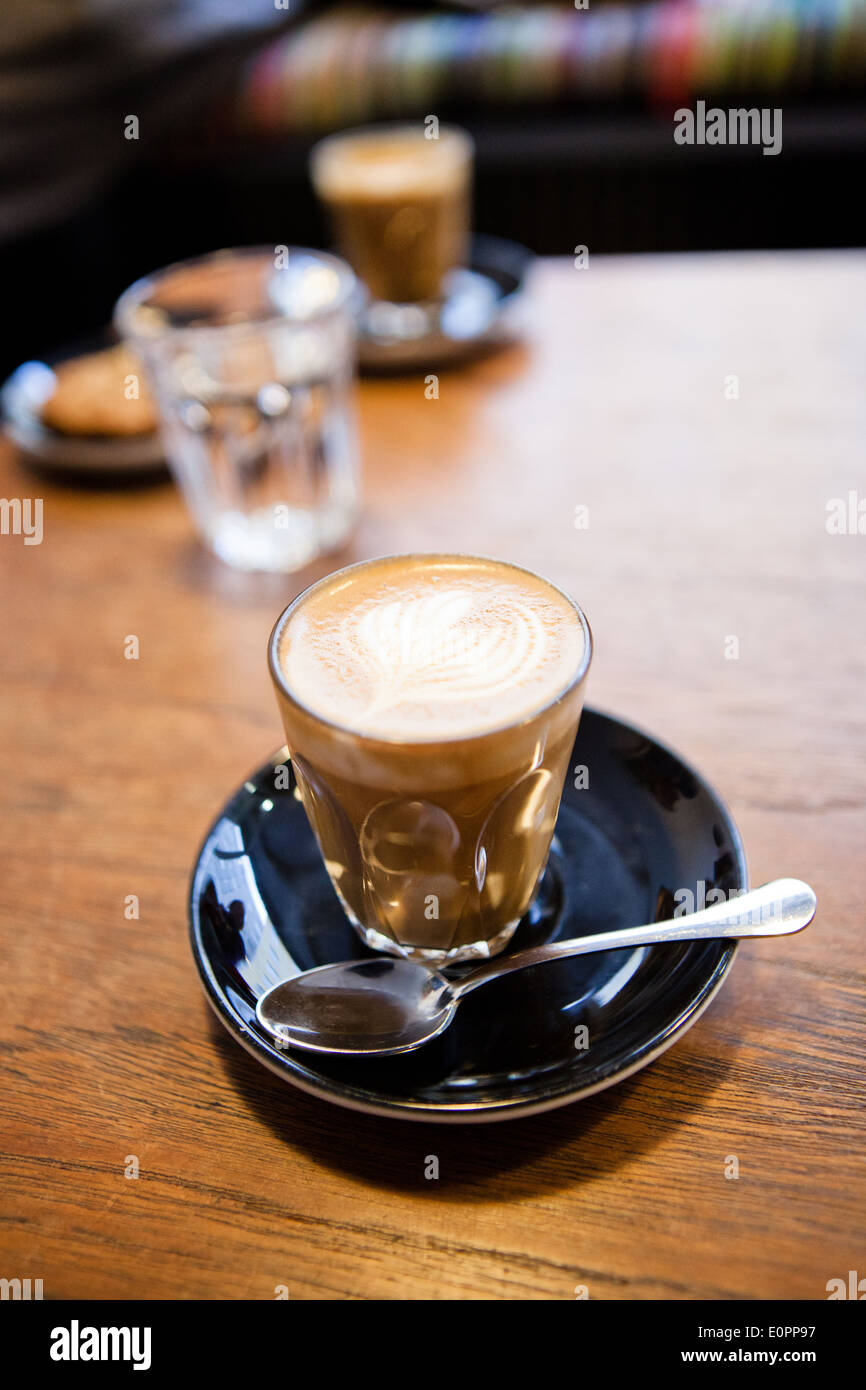 Libre de l'espresso et de lait latte en verre avec forme de coeur coffee art design reposant sur une soucoupe sur la table en bois Banque D'Images