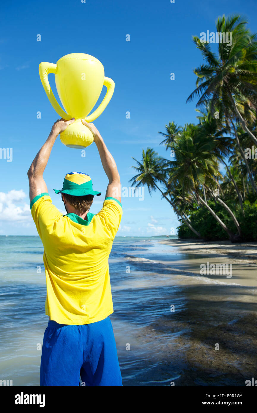 Joueur de football brésilien, l'équipe de couleurs Brésil holding trophy jusqu'à la plage de Nordeste Bahia Banque D'Images