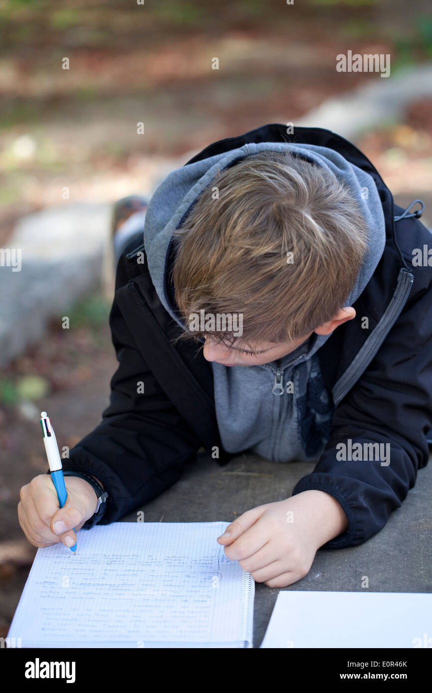 Écolier gisant sur un banc de pierre avant de faire ses devoirs à l'école à l'extérieur. Banque D'Images