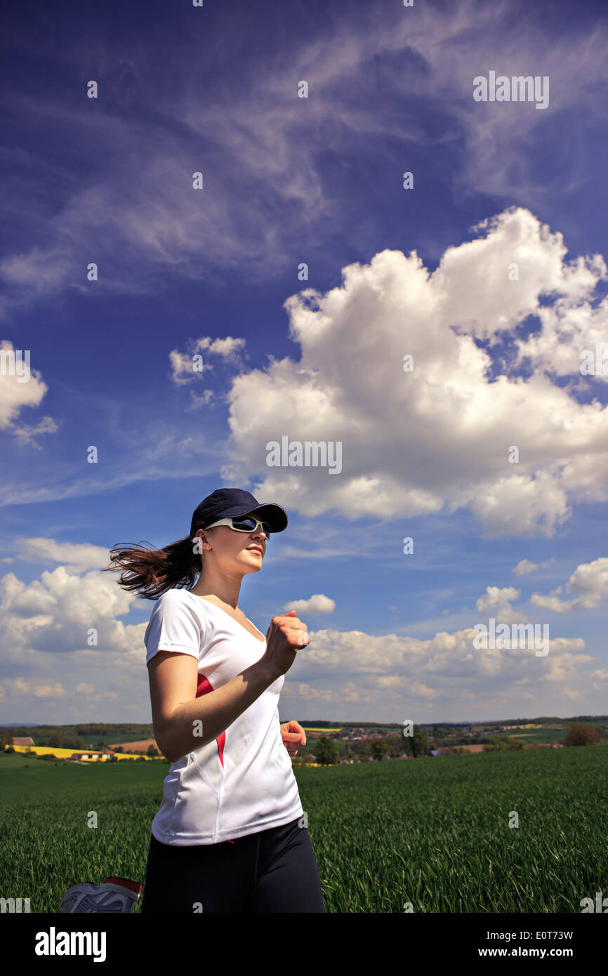 Woman jogging à travers champs au printemps Banque D'Images