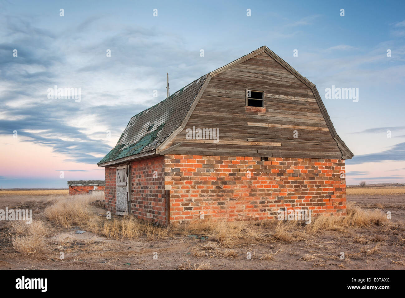 Grange en briques abandonnées et les bâtiments agricoles dans l'est du Colorado prairie au crépuscule Banque D'Images