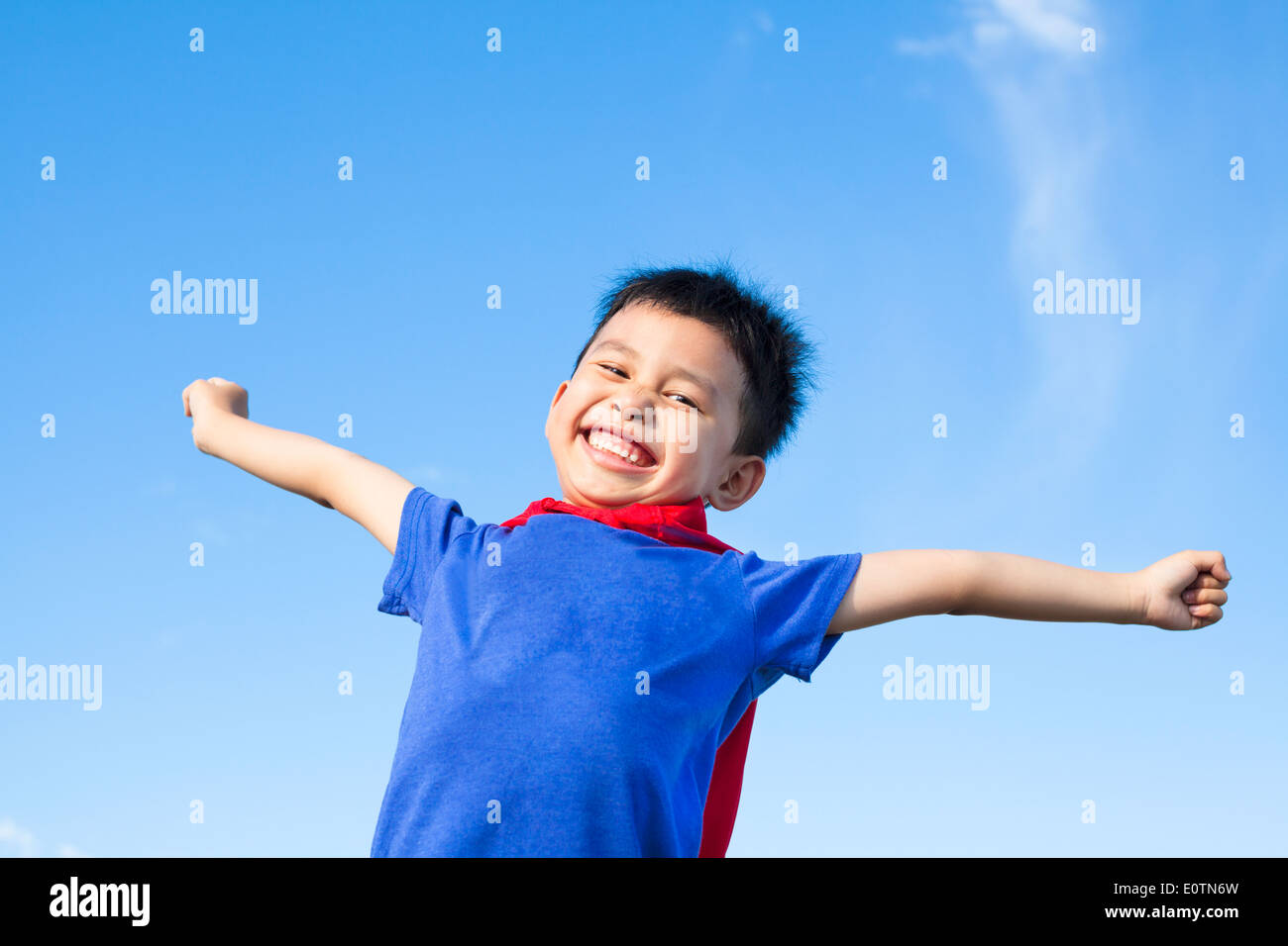 Petit garçon heureux et super-héros imitent les bras ouverts avec ciel bleu Banque D'Images
