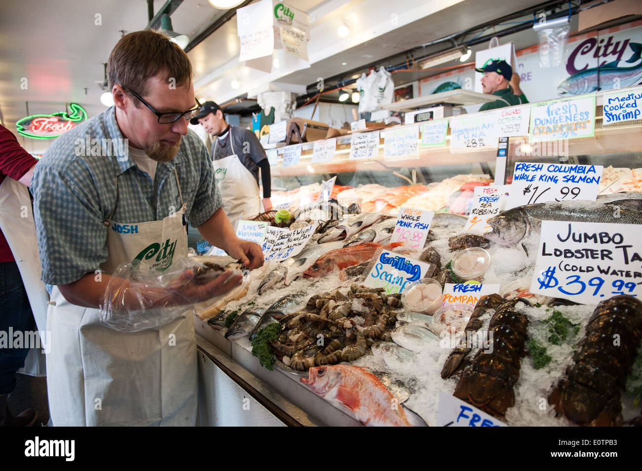 Un employé de ville Fish Co. organise des crevettes au Pike Place Market, à Seattle. Banque D'Images