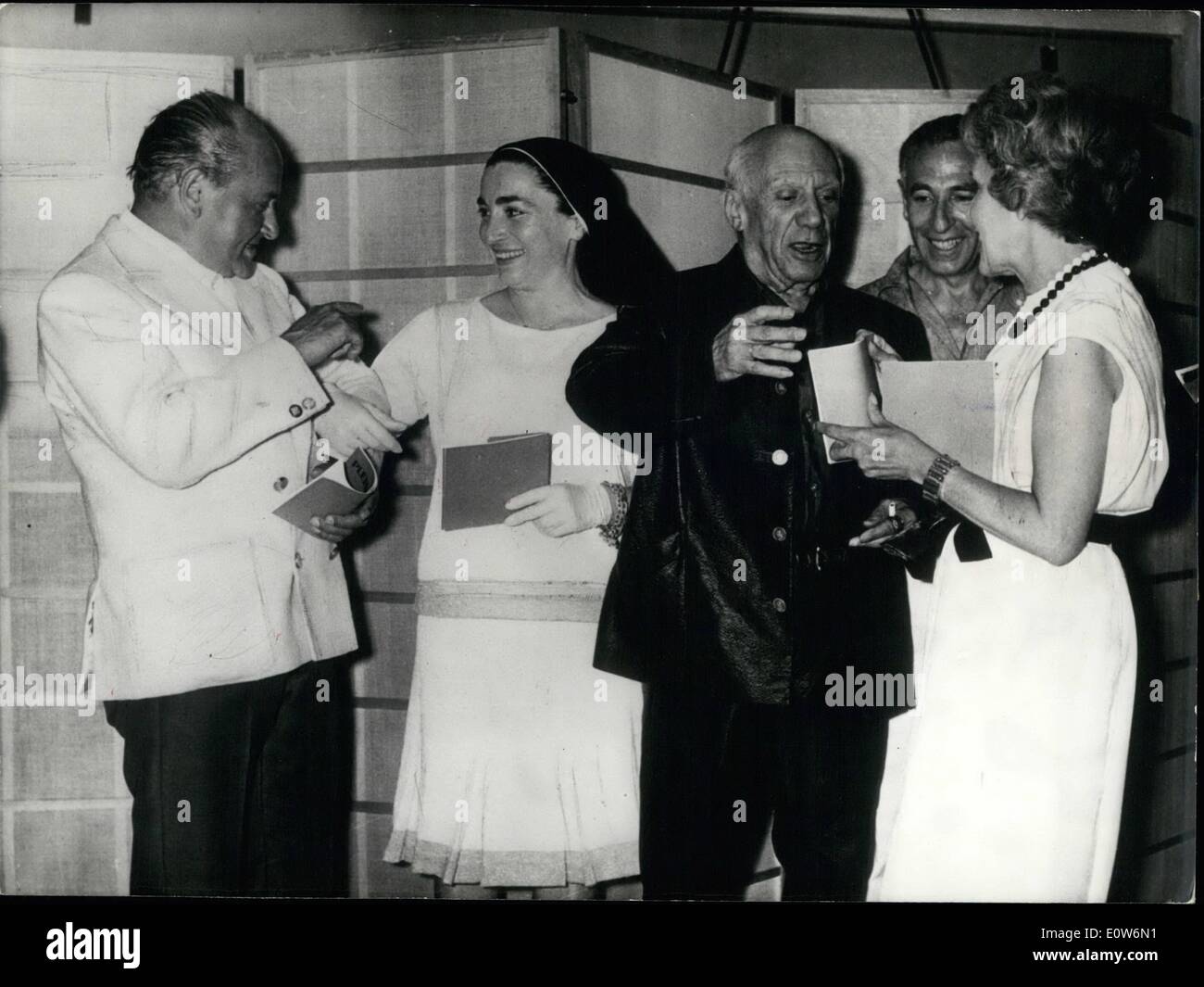 08 août 1961 - Noir et Blanc:Pablo Picasso reste fidèle à son manteau de cuir noir et un pantalon : Pablo Picasso offre un saisissant avec son manteau de cuir noir et un pantalon noir parmi les robes blanches de sa jeune épouse Jacqueline (gauche et de Mme de la ramie, propriétaire d'une galerie d'art à Cannes, Côte d'Azur. Cette photo a été prise hier, lors de l'ouverture de l'exposition de céramique à Mme. La Galerie de ramie.représentent également sont Alex Maguy (à gauche). Ancien Couturier maintenant propriétaire d'une galerie d'art dans le célèbre Saint-honoré et M. Verdet (entre Picasso et Mme Banque D'Images