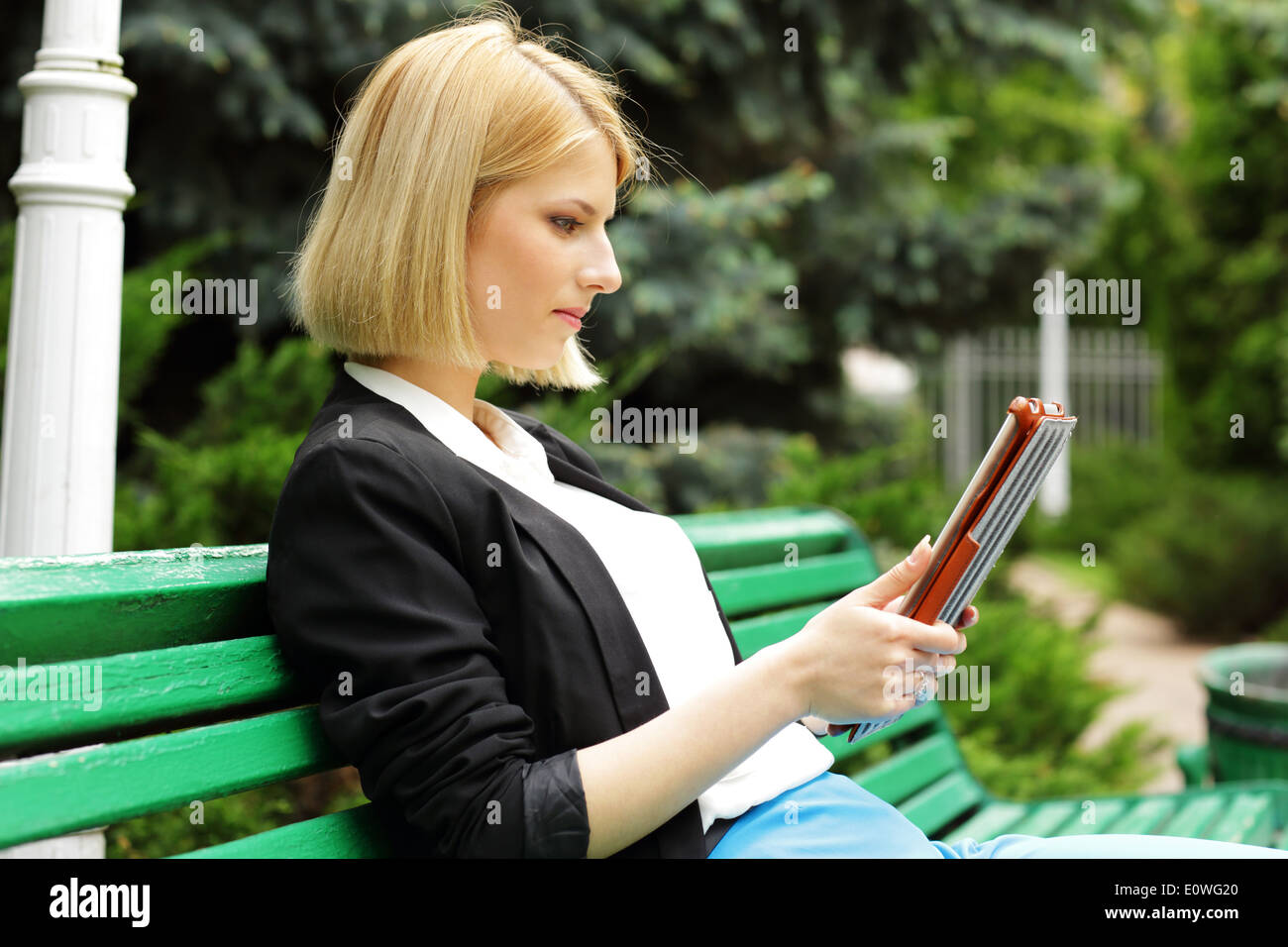 Belle Jeune femme assise sur le banc de la rue avec l'ordinateur de table Banque D'Images