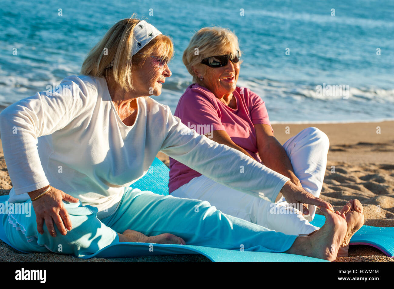 Les femmes âgées de faire des exercices d'étirement sur plage. Banque D'Images